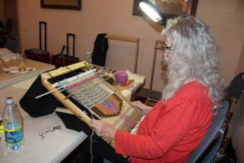 Student Pam Root leans the loom on a table.  