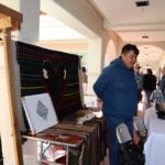 Nikyle Begay assisted Zefren with sales while Zefren demonstrated weaving. Zefren's wonderful Colors May Fade weaving is behind Nikyle.