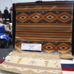 The larger piece is a squash blossom design that Leona says reminded her of her first rug. The small pictorial depicts male (on the left) and female (on the right) corn figures.